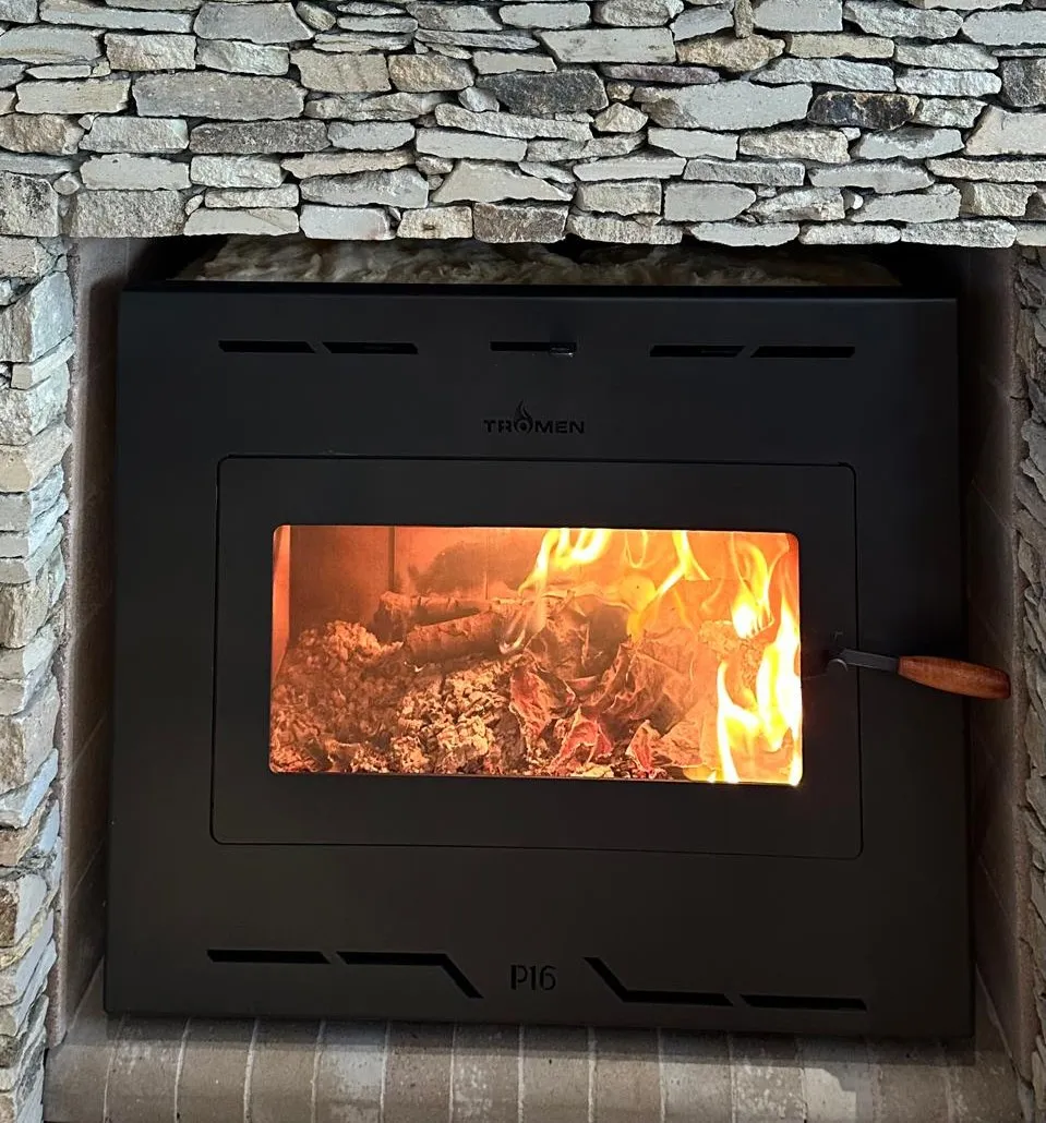 Tromen heater embedded in a stone wall with lighted fire