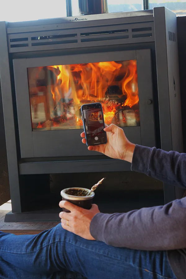 A man with a mate takes a picture of his Tromen wood heater.