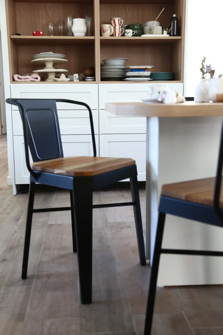 Una sillas de madera y metal acomodada debajo de una mesa
