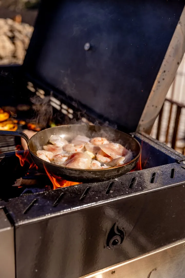 Steel frying pan with white meat on a grill